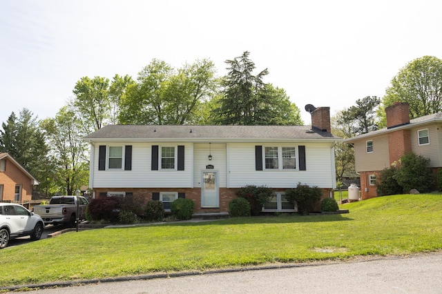 bi-level home with brick siding, a chimney, a front yard, and entry steps