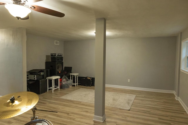 basement with baseboards, a ceiling fan, wood finished floors, and visible vents