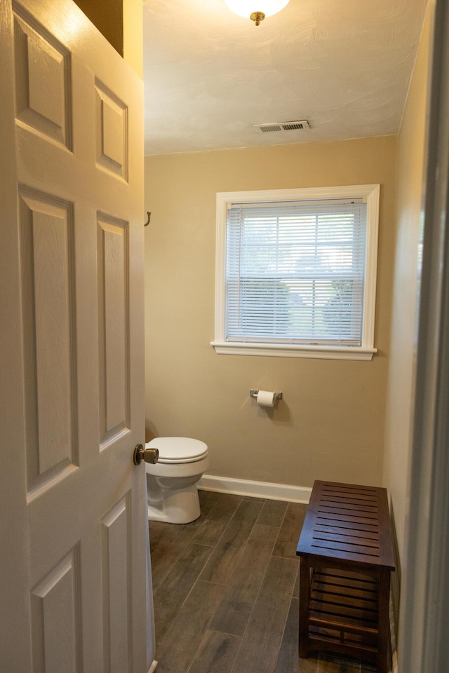 bathroom featuring toilet, baseboards, visible vents, and wood finished floors