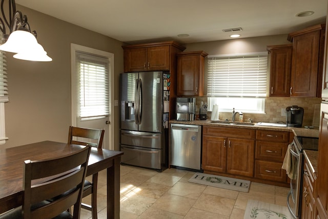 kitchen featuring decorative backsplash, appliances with stainless steel finishes, a healthy amount of sunlight, and a sink