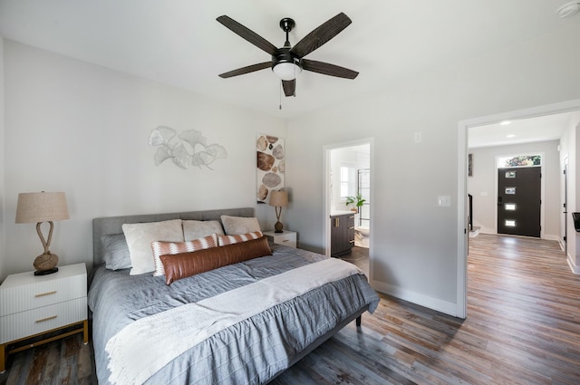 bedroom featuring ceiling fan, baseboards, multiple windows, and wood finished floors