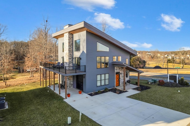 contemporary home with a wooden deck, driveway, a chimney, and a front yard