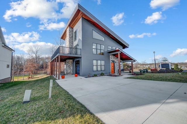 exterior space with concrete driveway, stone siding, and a front yard