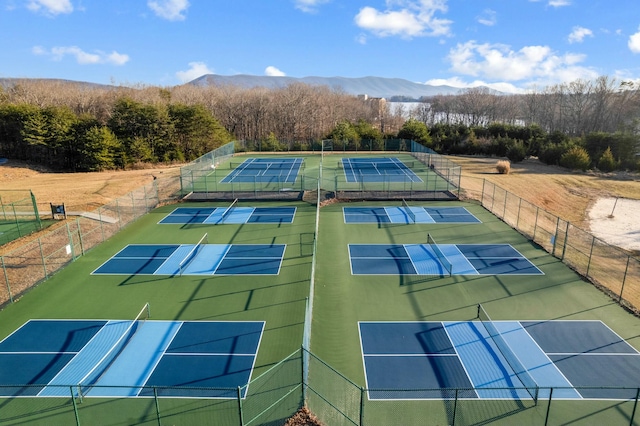 view of tennis court featuring community basketball court, fence, and a mountain view