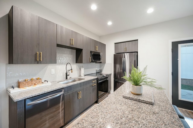 kitchen featuring light stone counters, appliances with stainless steel finishes, decorative backsplash, and a sink