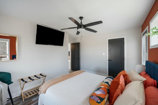 bedroom with baseboards, a ceiling fan, wood finished floors, and multiple windows