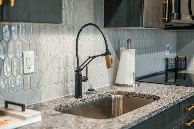 details featuring backsplash, light stone countertops, and a sink