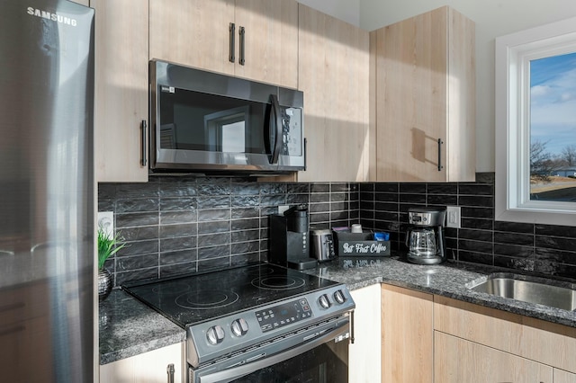 kitchen featuring dark stone counters, backsplash, light brown cabinetry, and stainless steel appliances