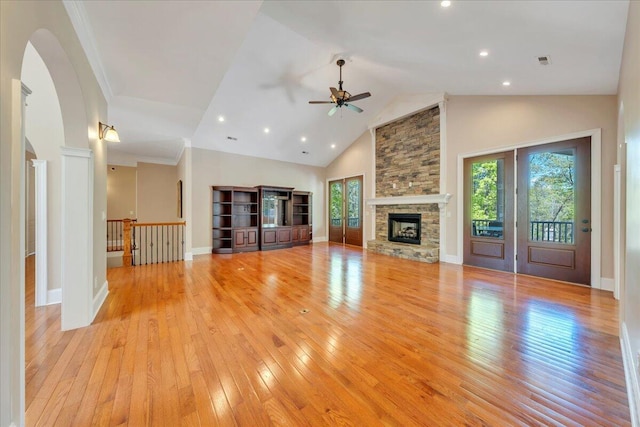 unfurnished living room with light wood finished floors, a ceiling fan, a wealth of natural light, and a fireplace