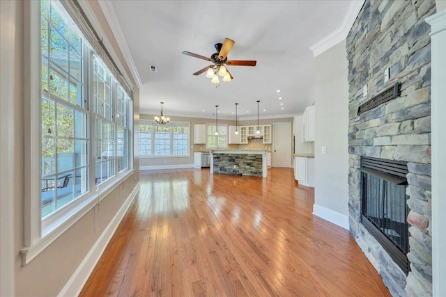 unfurnished living room featuring baseboards, ornamental molding, light wood-style flooring, and a fireplace