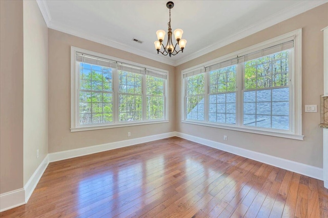 unfurnished dining area featuring baseboards, an inviting chandelier, crown molding, and wood-type flooring
