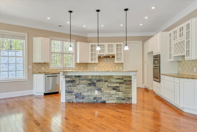 kitchen featuring tasteful backsplash, light wood-style flooring, light stone counters, appliances with stainless steel finishes, and white cabinets