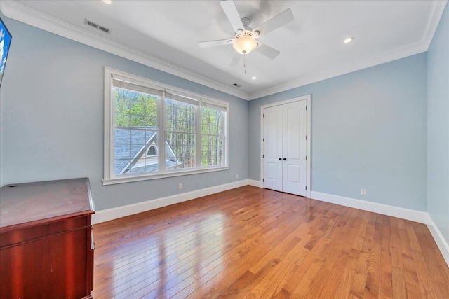 unfurnished bedroom with light wood-style floors, a closet, visible vents, baseboards, and ornamental molding