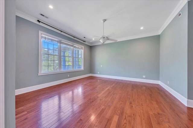 spare room featuring ornamental molding, visible vents, wood finished floors, and baseboards