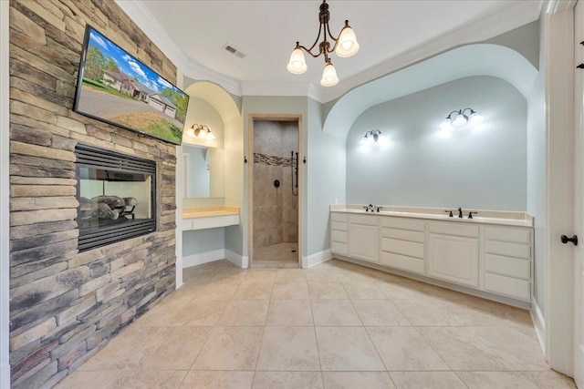 full bath featuring tiled shower, ornamental molding, a fireplace, a sink, and visible vents