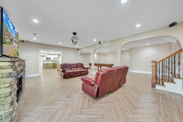 living area with baseboards, arched walkways, recessed lighting, a fireplace, and stairs