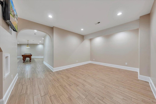empty room with arched walkways, pool table, light wood finished floors, baseboards, and visible vents