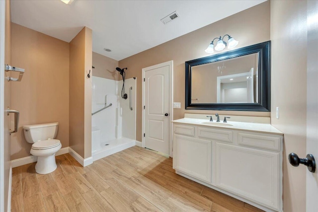 bathroom featuring toilet, visible vents, baseboards, walk in shower, and wood finished floors
