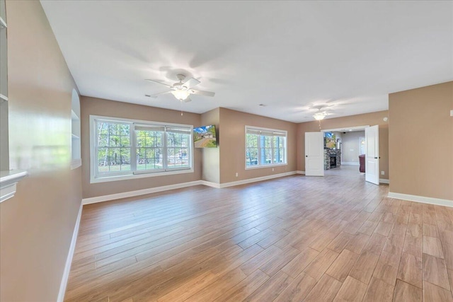 unfurnished living room featuring baseboards, ceiling fan, and light wood-style floors