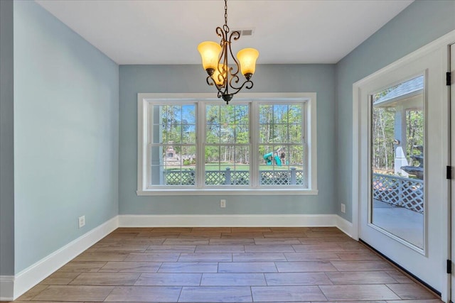 unfurnished dining area featuring a chandelier, wood finish floors, and baseboards