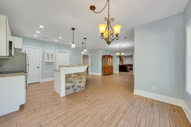 kitchen featuring a chandelier, baseboards, light wood-type flooring, and stainless steel microwave