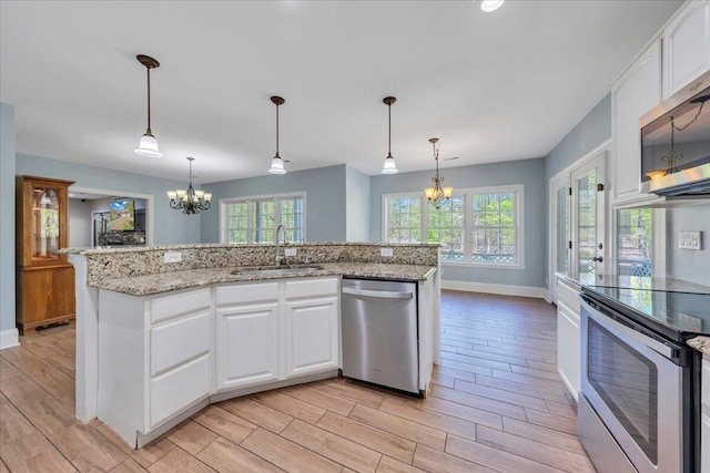 kitchen with appliances with stainless steel finishes, a chandelier, baseboards, and a sink