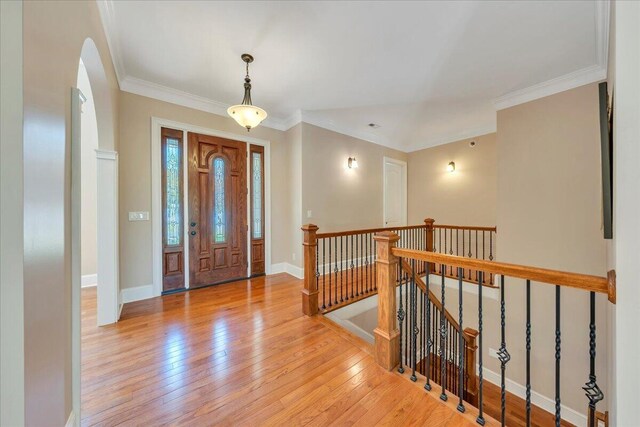 foyer with crown molding, light wood-style flooring, and baseboards