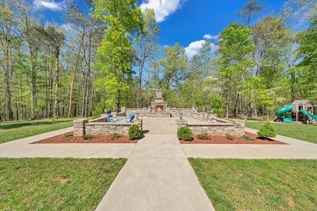 exterior space with a yard, a playground, a forest view, and a patio area