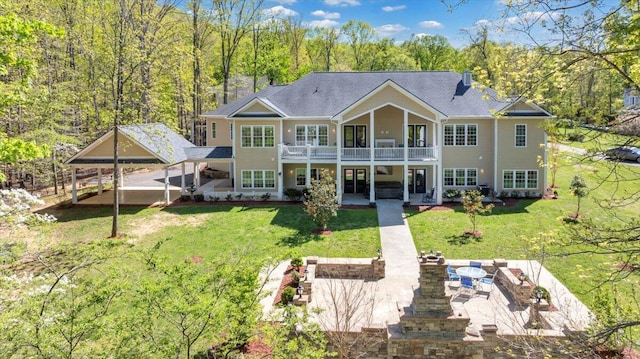 rear view of house with an outdoor fire pit, a patio area, a balcony, and a lawn