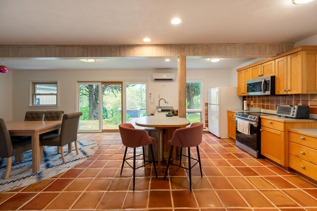 kitchen with recessed lighting, a wall unit AC, a breakfast bar area, backsplash, and appliances with stainless steel finishes