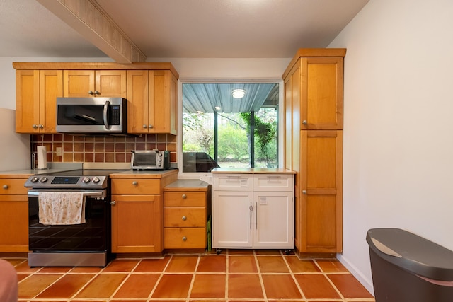 kitchen featuring light tile patterned flooring, stainless steel appliances, light countertops, and backsplash