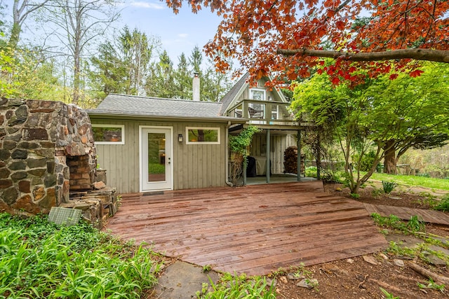 back of house featuring a deck, a chimney, and a shingled roof
