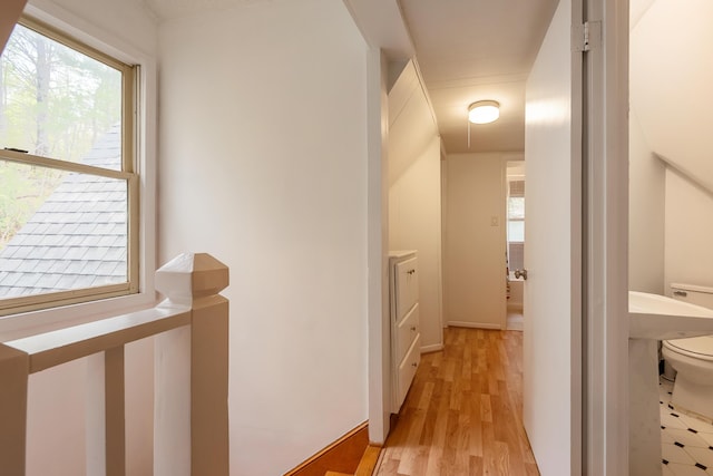 corridor featuring an upstairs landing, a wealth of natural light, and light wood-style floors