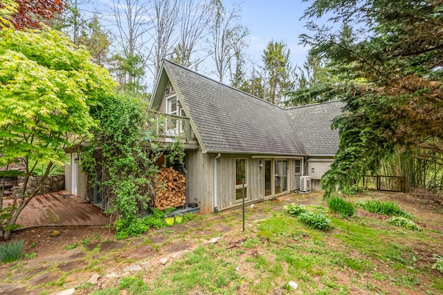 rear view of property featuring a deck, central air condition unit, and a shingled roof