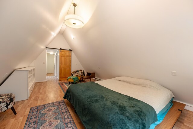 bedroom featuring baseboards, lofted ceiling, and light wood finished floors