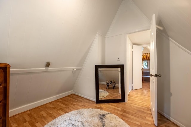 additional living space featuring baseboards, wood finished floors, and vaulted ceiling