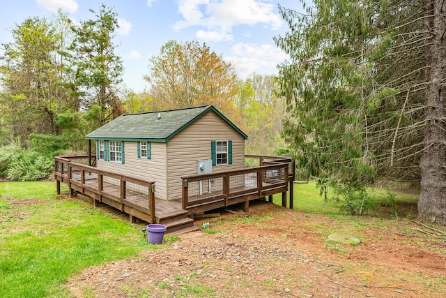 rear view of property featuring a deck, a yard, and a shingled roof