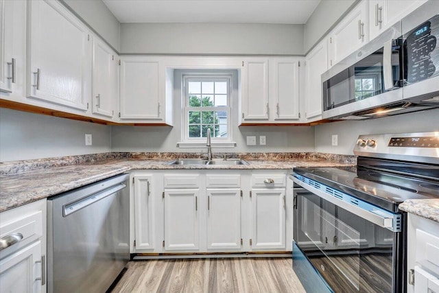 kitchen featuring a sink, white cabinets, stainless steel appliances, and light wood finished floors