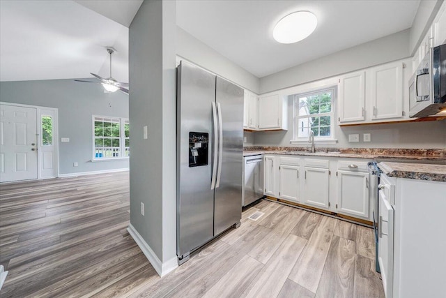 kitchen with a sink, light wood finished floors, appliances with stainless steel finishes, and white cabinets