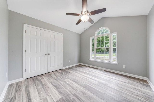 unfurnished bedroom with baseboards, a closet, light wood-style flooring, and lofted ceiling