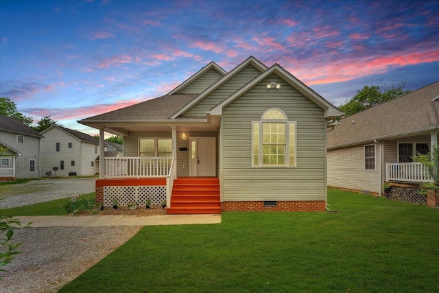 bungalow with driveway, a porch, a front lawn, and crawl space