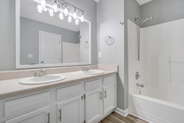 bathroom with a sink, washtub / shower combination, double vanity, and wood finished floors