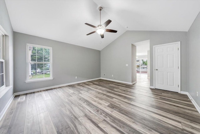 interior space with wood finished floors, a ceiling fan, baseboards, and lofted ceiling