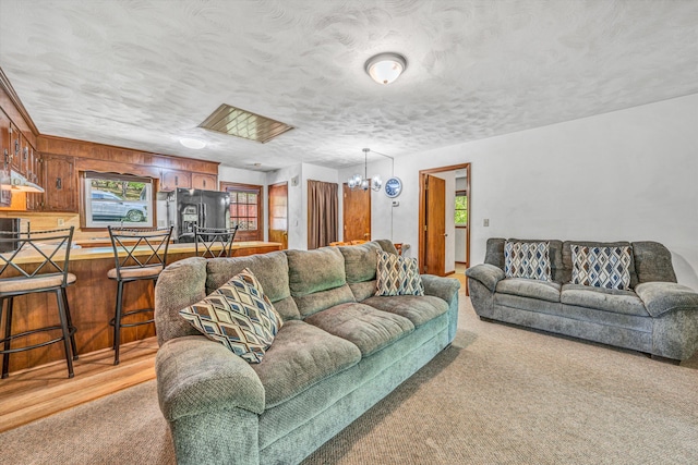 living room with wooden walls, light colored carpet, and a chandelier