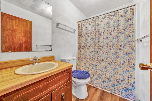 bathroom with toilet, vanity, a shower with curtain, and wood finished floors