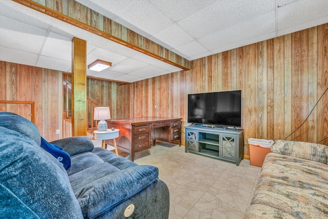 living area with wooden walls and a drop ceiling
