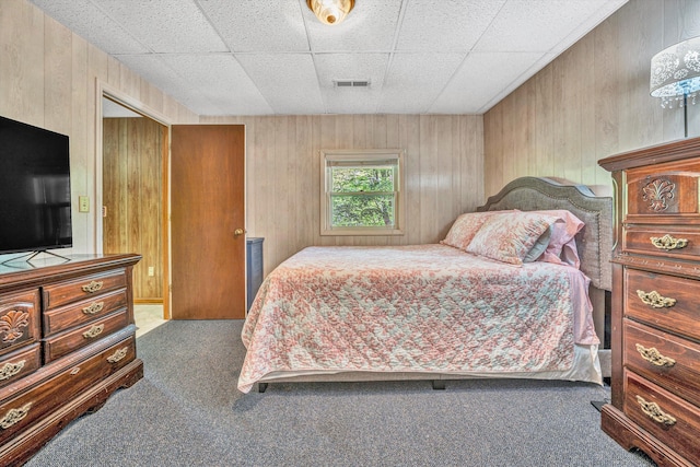 carpeted bedroom with visible vents and wood walls