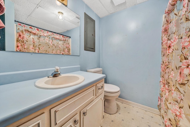 bathroom with a paneled ceiling, vanity, tile patterned floors, toilet, and baseboards