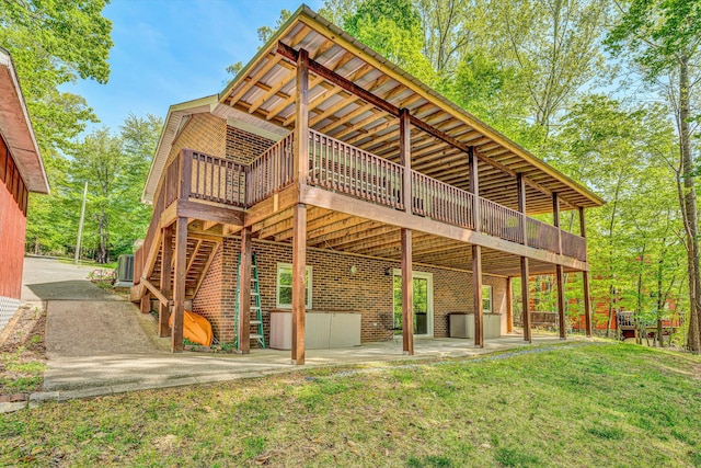 back of property featuring a wooden deck, a patio area, and a lawn