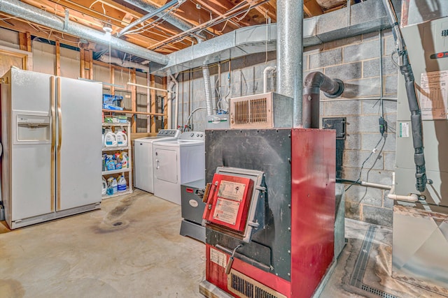 unfinished below grade area featuring white refrigerator with ice dispenser, heating unit, and washing machine and clothes dryer